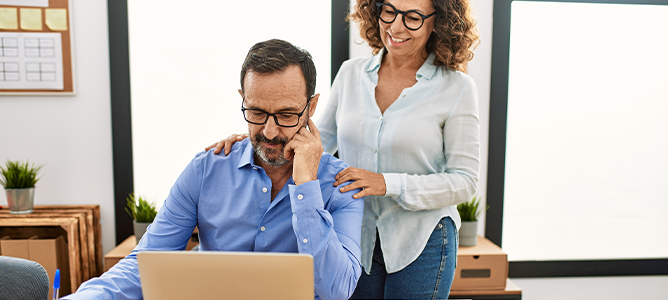 Wife standing behind husband working on the computer