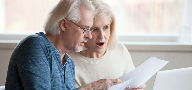 Surprised senior couple reviewing paperwork