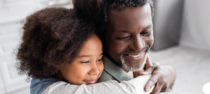 Young black girl hugging senior father