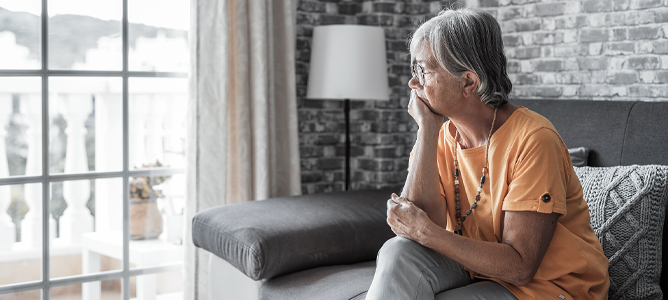Sad senior woman looking out window